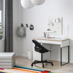 a white desk and chair in a room with lots of light colored rugs on the floor