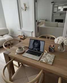 a laptop computer sitting on top of a wooden table next to a vase with flowers