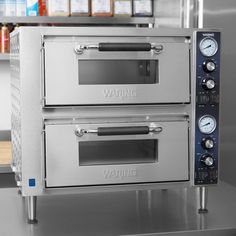 two stainless steel ovens sitting side by side on a counter in a commercial kitchen