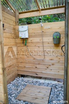 a wooden shower stall with gravel and rocks in the floor, surrounded by wood planks