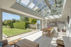 an open kitchen and living room with large windows on the side of the house that overlooks a lush green yard