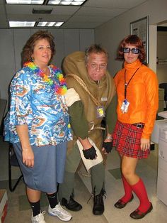 three people standing in an office with one person dressed as a man and the other wearing a woman's costume