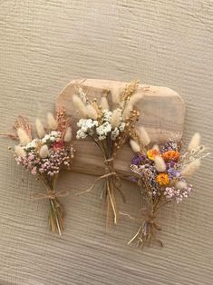 three dried flowers sitting on top of a wooden board