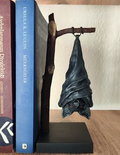 a bookend with a bat hanging from it's side next to two books