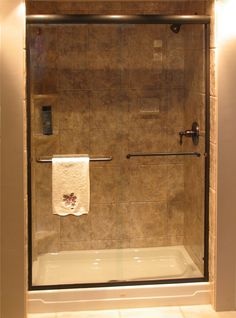 a bathroom with a glass shower door and tiled walls