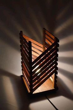 a lamp made out of wooden slats on a white surface with the light shining through it