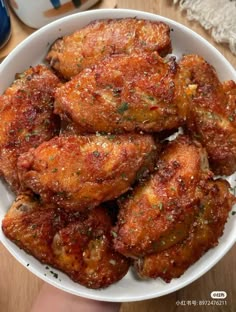 a white bowl filled with chicken wings on top of a wooden table