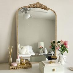 a mirror sitting on top of a white table next to a vase with flowers in it