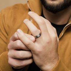 a man with a ring on his finger is looking at the camera while wearing a brown jacket