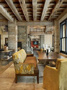 a living room filled with furniture and a fire place next to a stone wall covered in windows