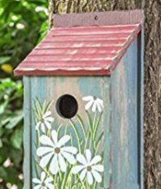 a birdhouse with flowers painted on it next to a tree