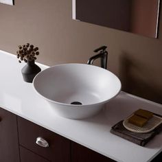 a white bowl sink sitting on top of a bathroom counter next to a black faucet