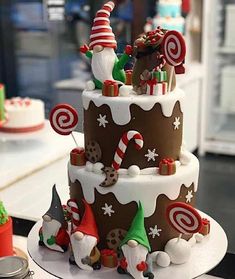 a three tiered cake decorated with candy canes and santa clause decorations on top