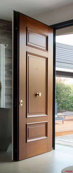 an open wooden door in front of a glass wall with a plant on the floor