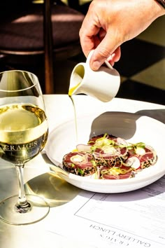 a person pours white wine into a plate of food