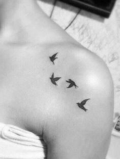 a woman's shoulder with birds flying in the air