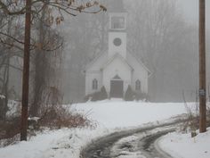 a white church with a clock tower in the snow