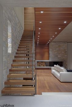 a living room filled with furniture next to a fire place under a stair case on top of a hard wood floor