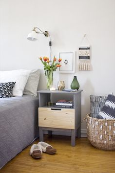 a bed room with a neatly made bed next to a night stand and two baskets on the floor