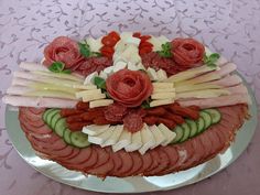 a platter filled with meats, cheese and veggies on top of a table