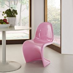 a pink chair sitting in front of a table with fruit on it and a potted plant