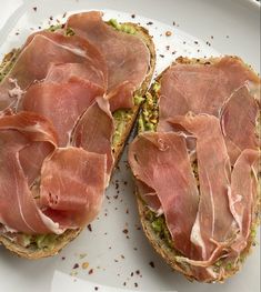 two open faced sandwiches with ham and pistachio toppings on a white plate