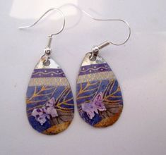 the earrings are decorated with purple flowers and silver hooks on white table top, ready to be used as jewelry