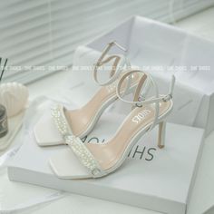 a pair of white high heeled shoes sitting on top of a box next to other items