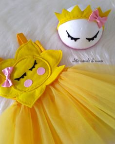 two stuffed animals in costumes on a white furnishing surface, one is wearing a yellow tutu and the other has a pink bow