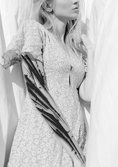 black and white photograph of a woman leaning against a curtain