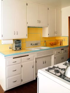 a kitchen with white cabinets and yellow backsplash on the counter top, along with a tea kettle