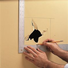 a man holding a pencil in front of a torn piece of paper on a wall