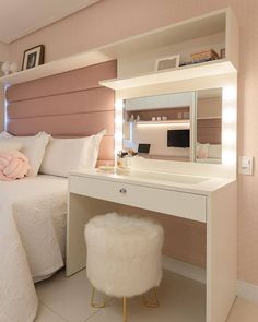 a bedroom with a bed, desk and mirror in the corner that has lights on