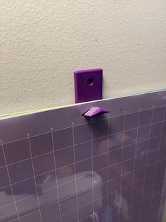 a purple wall mounted on the side of a white tiled wall next to a toilet