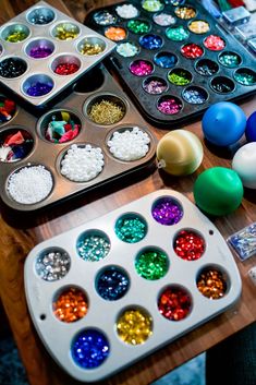 there are many different colors of beads in the trays on the table next to each other