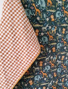 an orange and white checkered blanket next to a black and white checked pillow with animals on it