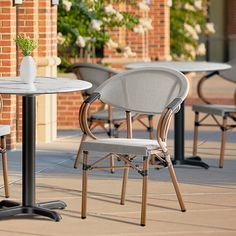 two chairs and a table with wine glasses on top of it outside in front of a brick building