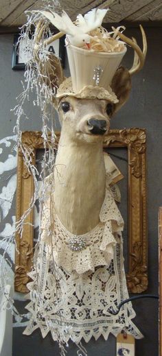 a sculpture of a deer with a hat on it's head is hanging from a wall