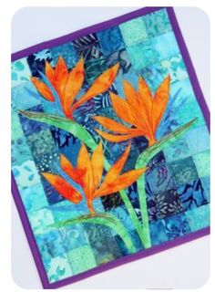 two orange flowers on a blue and green patchwork quilted square with purple border