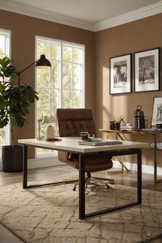 a living room with a couch, chair and desk in front of two large windows