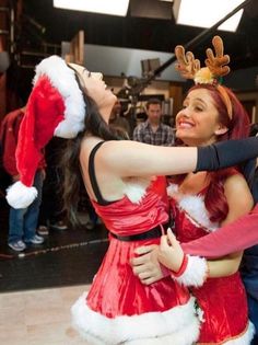 two people dressed as santa clause and reindeer hats hugging each other on the dance floor