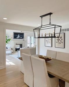 a dining room table with white chairs and a chandelier hanging from the ceiling