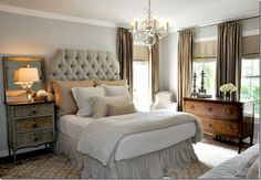 a bed sitting in a bedroom under a chandelier next to a window with curtains