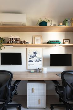 an office with two desks and three computer screens on the wall above them,