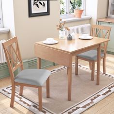 a dining table with two chairs and a rug on the floor