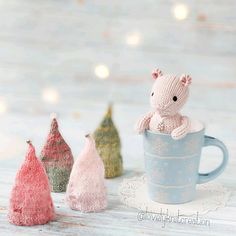 three small knitted animals sitting in a coffee cup next to each other on a table