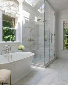 a bathroom with a large tub and walk in shower next to a white toilet sitting under a window