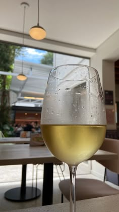 a glass of white wine sitting on top of a table