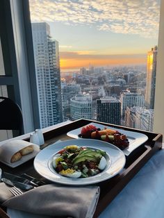 a plate of food on top of a table in front of a window overlooking the city