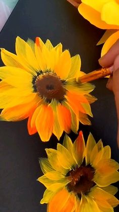 someone is painting sunflowers with yellow and orange colors